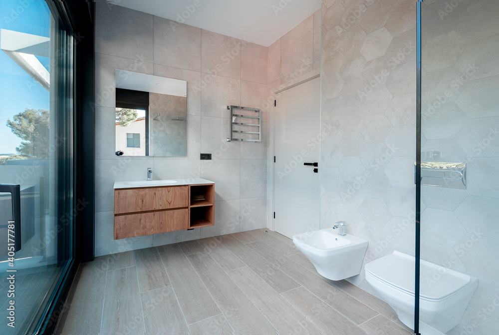 Modern bathroom with gray diamond and rectangle tiles. Large shower with glass railing.
