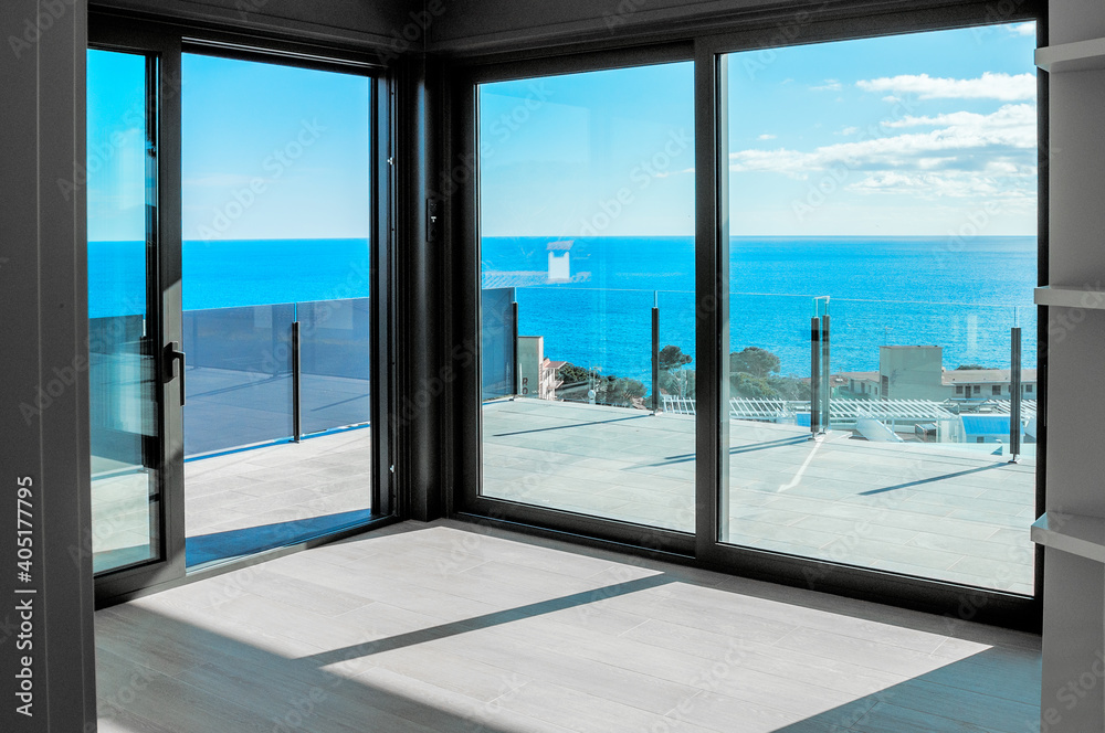 Empty room with large panoramic windows overlooking the sea. Room after major renovation.