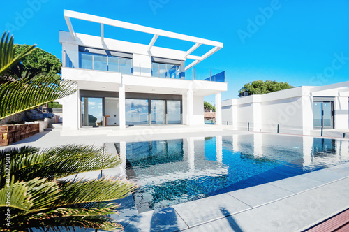 The modern facade of a luxury villa with a large swimming pool. Luxury MODERN property. © steftach