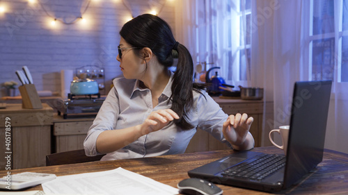 nervous young businesswoman working overtime late in home office. scared lady worker working on laptop computer and turn head around looking for some strange sound in back kitchen. weird in evening.