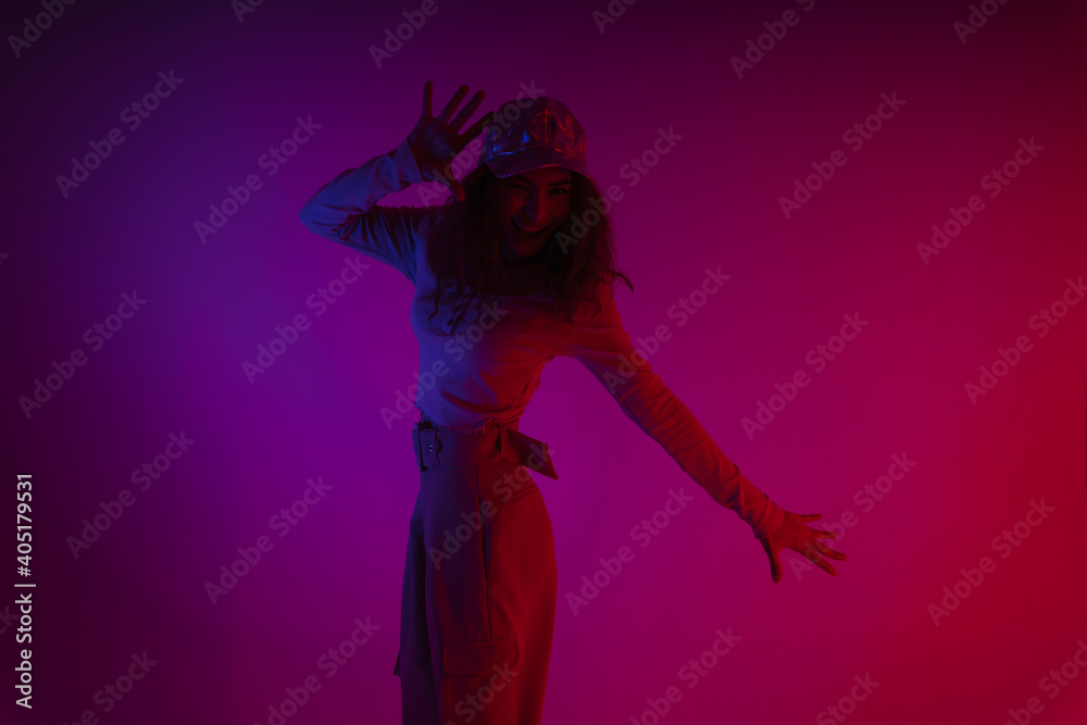 Portrait of hipster woman dancing in dark neon light background.