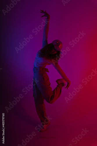 Portrait of hipster woman dancing in dark neon light background.