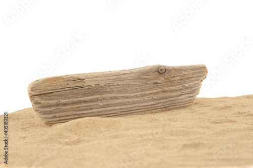 Driftwood on sand isolated on white background. Piece of coastal weathered wood on sand dune.