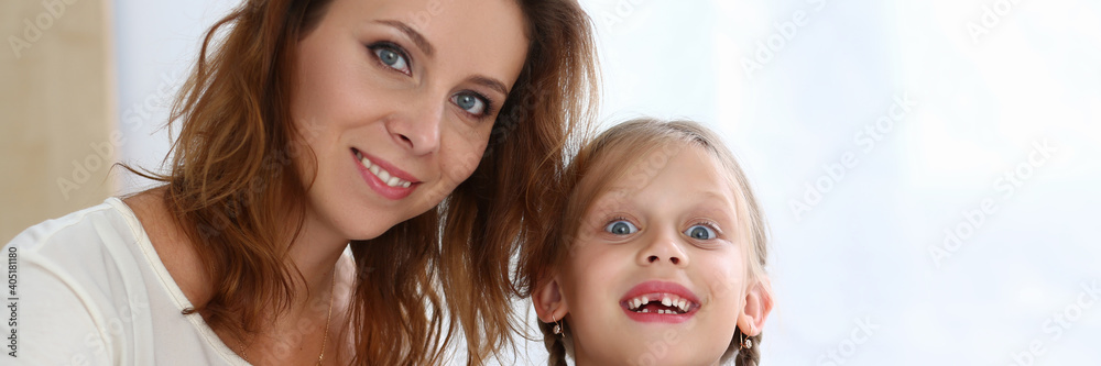 Portrait of cheerful woman with her child while they are sitting at table and reading book Portrait of cheerful woman with her child while they are sitting at table and reading book
