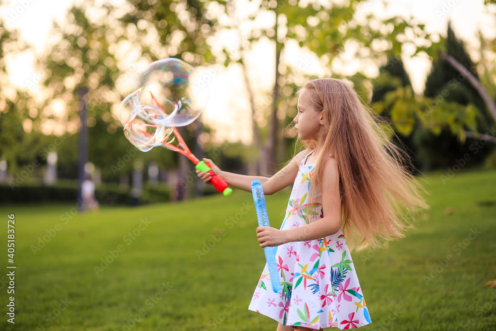 Happy little girl playing with summer soap bubbles in the park. Happy little girl playing with summer soap bubbles in the park.