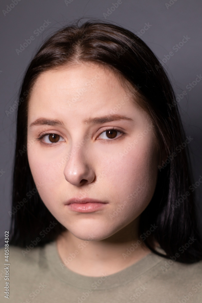 Obraz premium portrait of charming sad brunette woman in marsh color t-shirt on grey wall background. actress acting, emotion