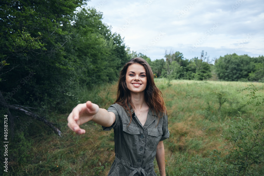 Woman portrait on nature in a green overalls smile with an outstretched hand Woman portrait on nature in a green overalls smile with an outstretched hand