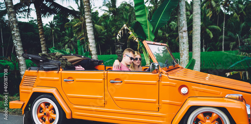 Serious couple in retro orange car in tropical city photo