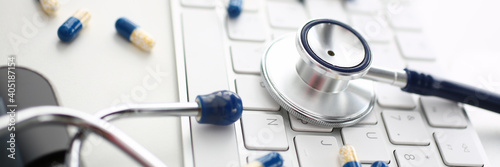 Focused photo on metal part of stethoscope that being on keyboard, working place of practitioner