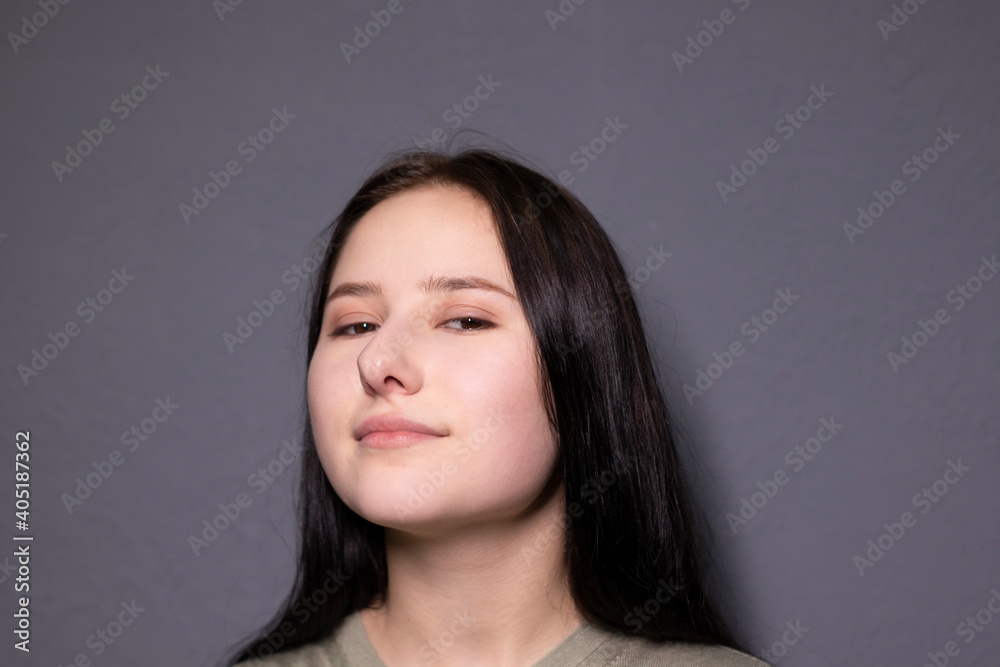 portrait of charming happy brunette woman in marsh color t-shirt on grey wall background. actress acting, emotion.