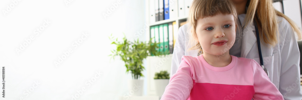 Happy child is sitting on female laps during her working day as doctor in hospital Happy child is sitting on female laps during her working day as doctor in hospital