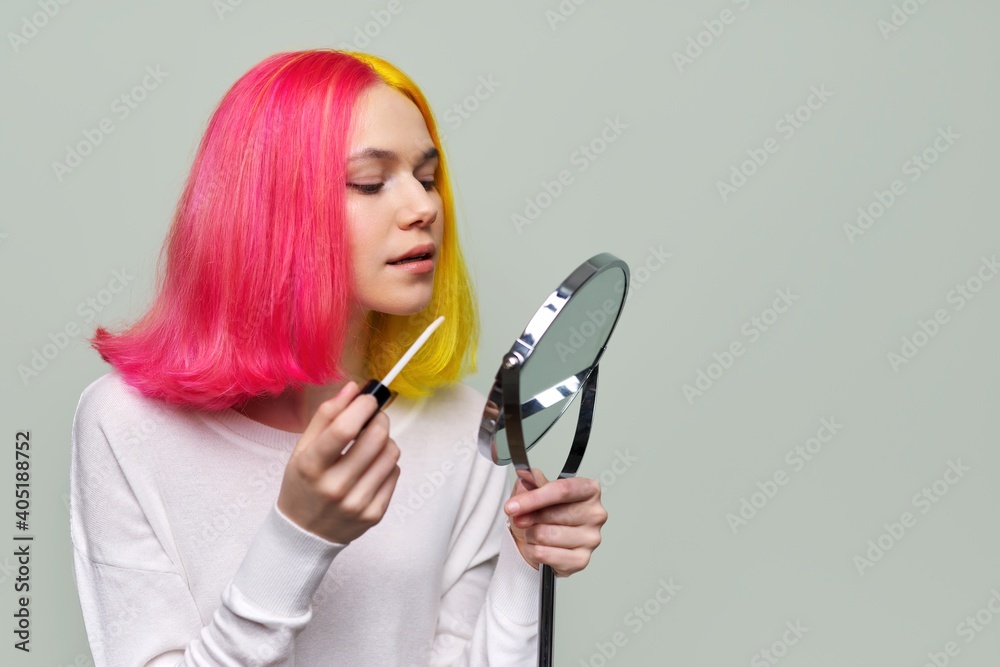 Fashionable girl teenager with mirror for make-up painting lips with gloss Fashionable girl teenager with mirror for make-up painting lips with gloss