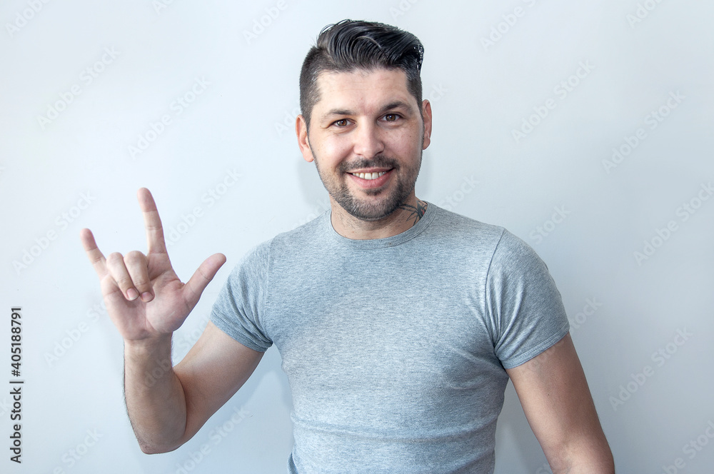  Portrait of a happy young man having fun and showing horns hand gesture. Depicting heavy metal rock sign.