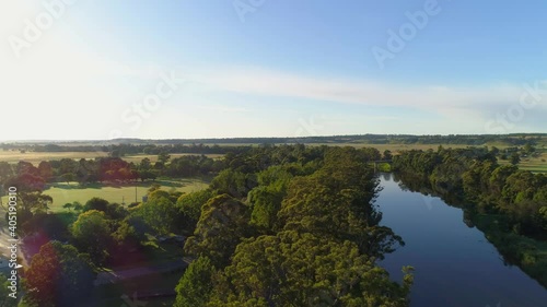 Forward flight low above tree-tops along riverbank at sunset photo