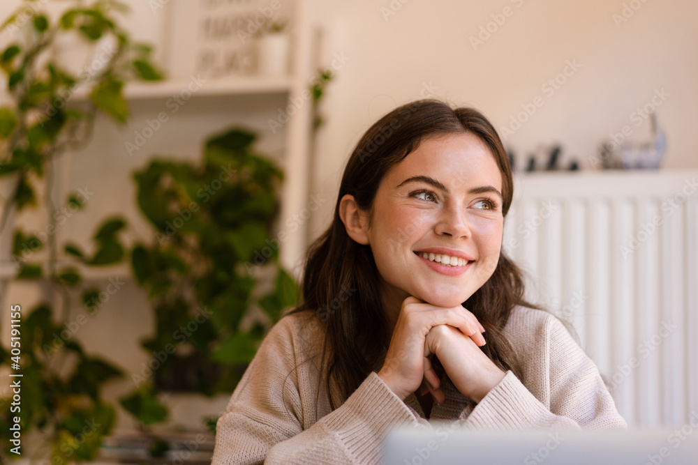 Happy charming girl smiling and looking aside while sitting in cafe Happy charming girl smiling and looking aside while sitting in cafe