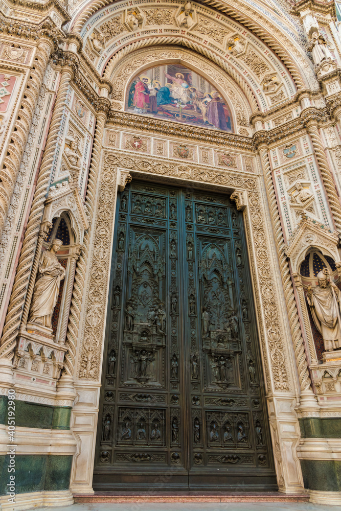 Great close-up view of Florence Cathedral's huge bronze doors of the central portal and a lunette above with a colourful mosaic of Christ enthroned with Mary and John the Baptist designed by Barabino.