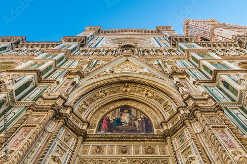 Impressive low-angle view of Florence Cathedral's main facade  from the lunette of the central portal with a colourful mosaic of Christ enthroned, up to the pediment, the rose window and the tympanum. © H-AB Photography