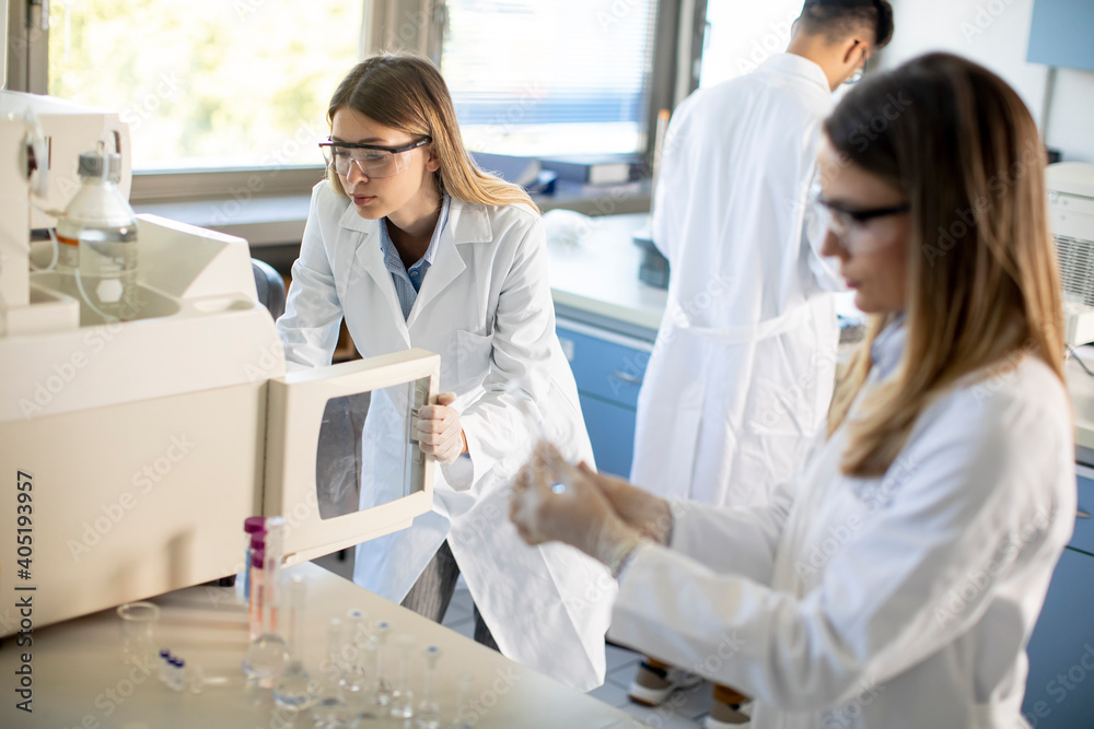Female scientists in a white lab coat putting vial with a sample for an analysis on a ionchromatography system in biomedical lab Female scientists in a white lab coat putting vial with a sample for an analysis on a ionchromatography system in biomedical lab