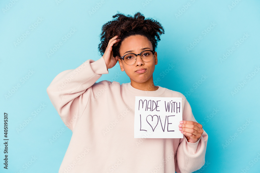 Young african american mixed race woman holding a made with love concept being shocked, she has remembered important meeting. Young african american mixed race woman holding a made with love concept being shocked, she has remembered important meeting.