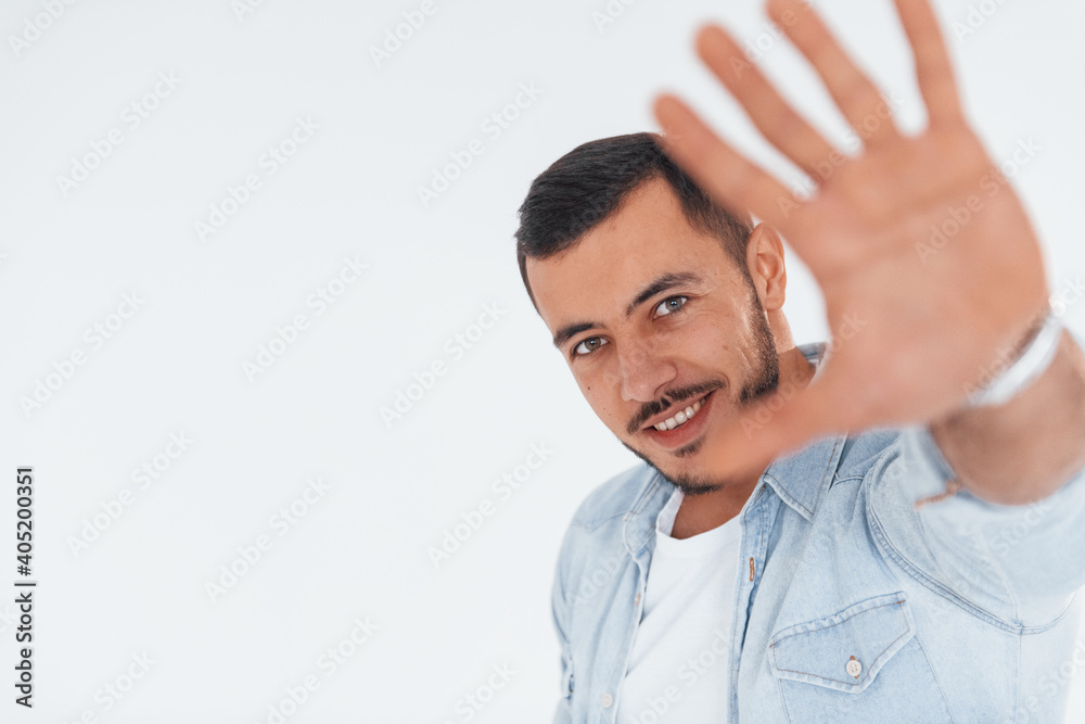 Stop gesture. Young handsome man standing indoors against white background Stop gesture. Young handsome man standing indoors against white background