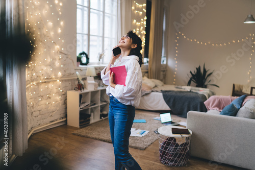 Happy woman talking on smartphone in cozy room