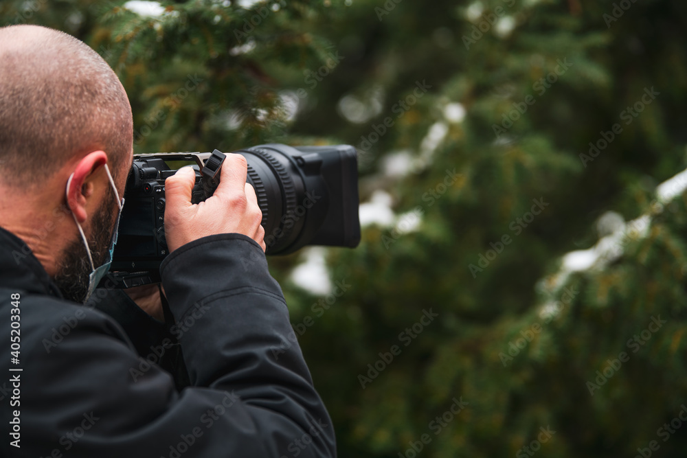 Close up view of a male photographed taking pictures with a mirrorless camera and a protective COVID-19 mask on its face Close up view of a male photographed taking pictures with a mirrorless camera and a protective COVID-19 mask on its face