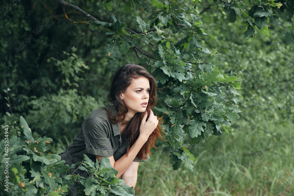 Woman in the forest sitting on the ground side view green leaves Woman in the forest sitting on the ground side view green leaves