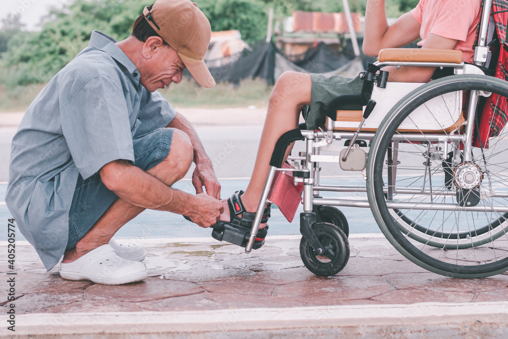 Obraz premium Asian special child on wheelchair and father in family time on public street, Parent attentive in boy daily missions, Lifestyle in the education age of disabled children, Happy disabled kid concept.