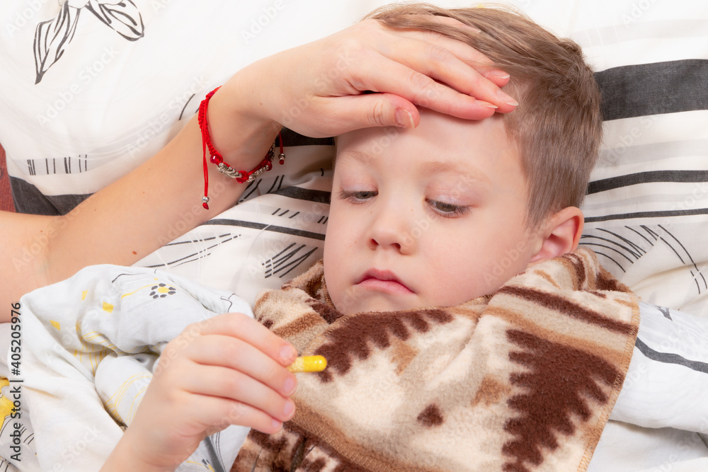 little boy child wrapped in a scarf is ill at home, lies in bed and drinks medicine little boy child wrapped in a scarf is ill at home, lies in bed and drinks medicine