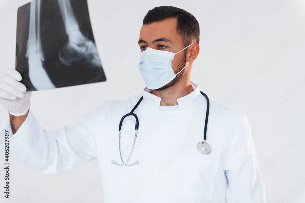 Medic with x-ray. Young handsome man standing indoors against white background Medic with x-ray. Young handsome man standing indoors against white background