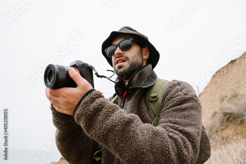 Focused photographer in sunglasses taking photo on digital camera