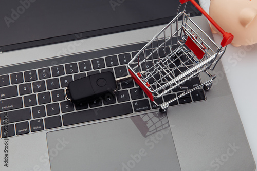 Car key and shopping trolley above laptop keyboard.