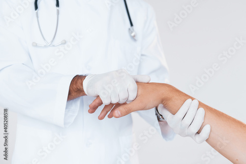 Medic works with patient s hand. Close up particle view of young man that standing indoors against white background