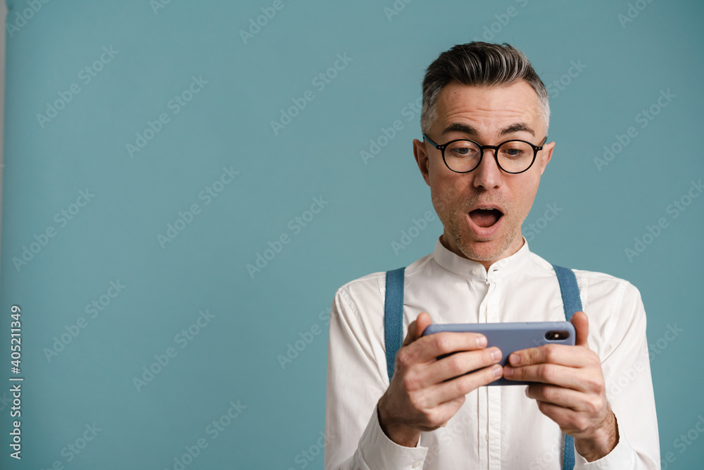 Shocked grey-haired man exclaiming while using cellphone Shocked grey-haired man exclaiming while using cellphone