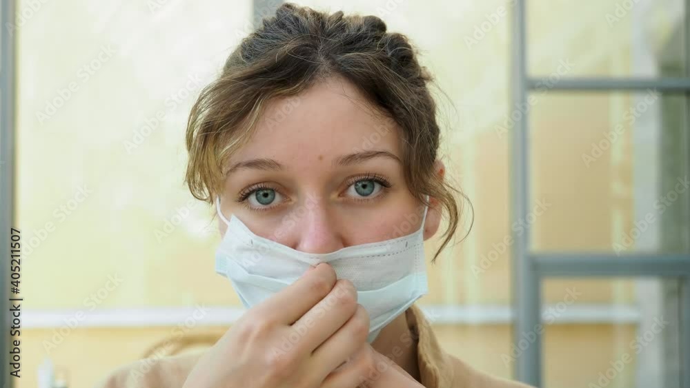 Portrait of a young dark curly haired woman wearing mask from coronavirus in cafe, looks at the camera. Safety life during quarantine. Self-isolation Portrait of a young dark curly haired woman wearing mask from coronavirus in cafe, looks at the camera. Safety life during quarantine. Self-isolation