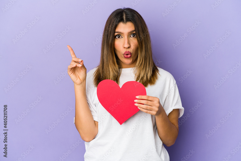 Young indian woman holding a valentines day heart isolated having some great idea, concept of creativity. Young indian woman holding a valentines day heart isolated having some great idea, concept of creativity.