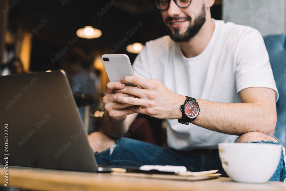 Cropped image of male programmer using cellphone technology for checking mobility notification, blurred blogger with electronic smartwatch using cellular gadget for online chatting and messaging Cropped image of male programmer using cellphone technology for checking mobility notification, blurred blogger with electronic smartwatch using cellular gadget for online chatting and messaging