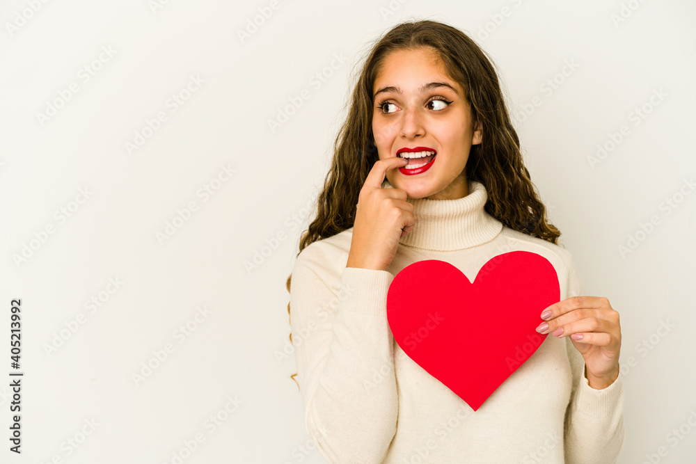Young caucasian woman holding a heart valentines day shape isolated relaxed thinking about something looking at a copy space. Young caucasian woman holding a heart valentines day shape isolated relaxed thinking about something looking at a copy space.