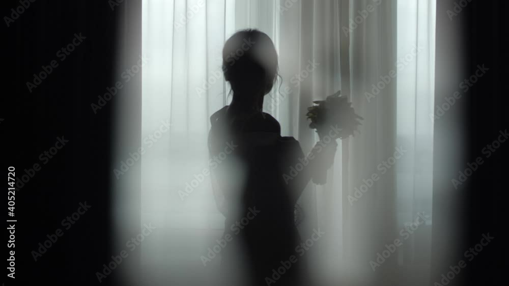 Silhouette of a girl at the window in a dark key. Wedding photo session ...