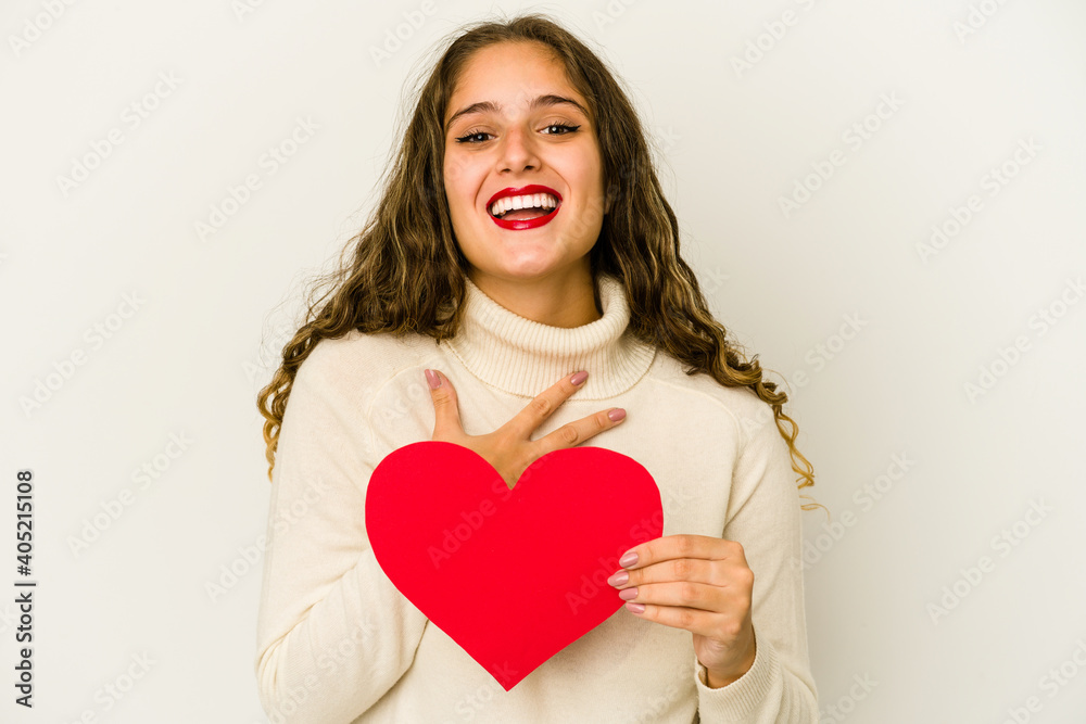 Young caucasian woman holding a heart valentines day shape isolated laughs out loudly keeping hand on chest. Young caucasian woman holding a heart valentines day shape isolated laughs out loudly keeping hand on chest.