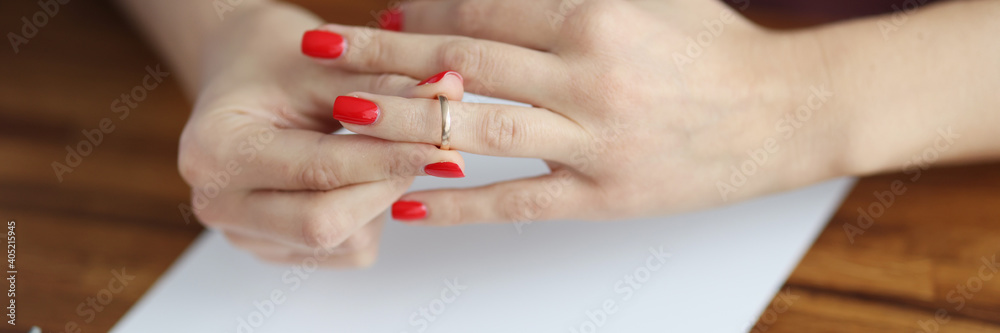 Woman's hand removes wedding ring from her finger. Family relationship and divorce concept Woman's hand removes wedding ring from her finger. Family relationship and divorce concept