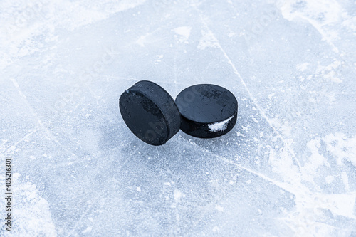 Two pucks are laying on the ice.