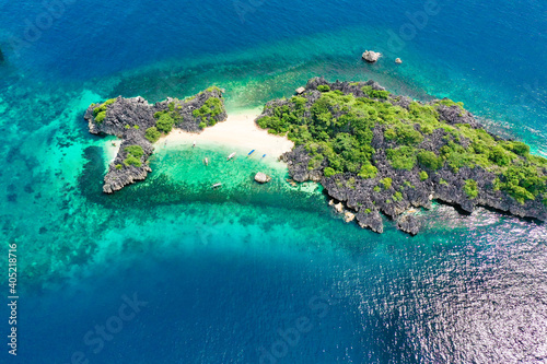 Aerial view of small isolated tropical island with white sandy beach and blue transparent water and coral reefs. photo