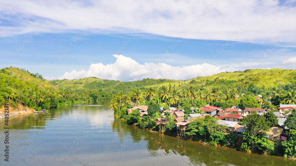 Countryside on a large tropical island. Small village on the green hills by the river. The nature of the Philippines.