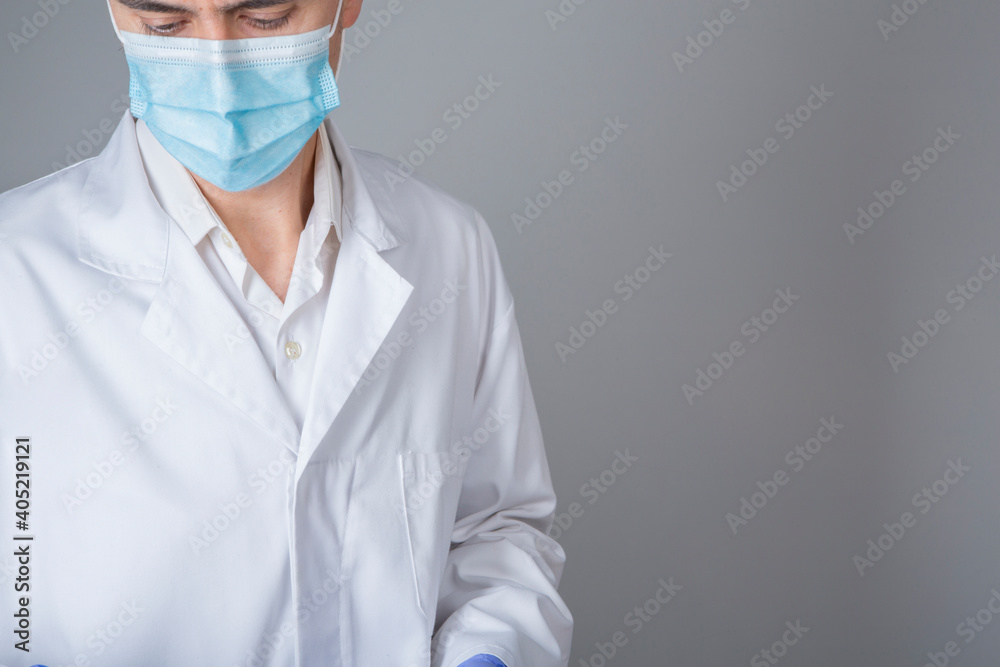 Doctor in white coat and blue mask on gray background Doctor in white coat and blue mask on gray background