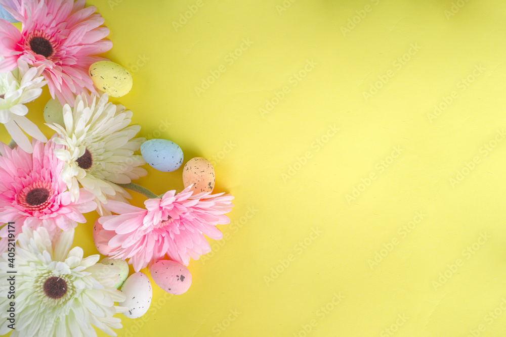 Easter greeting card background with gerbera flowers and colorful easter eggs. Top view flat lay on yellow background copy space for text