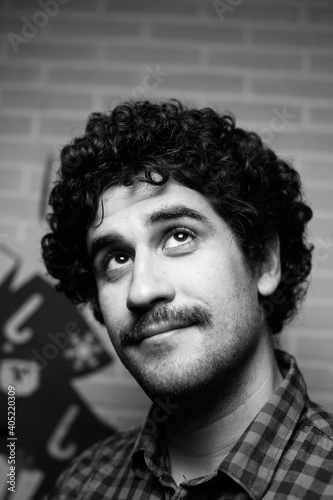 Black and white monochrome portrait of a red curly haired man with a mustache who looks like the scientist Einstein.