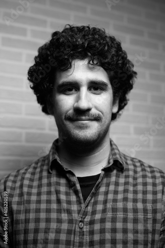 Black and white monochrome portrait of a red curly haired man with a mustache who looks like the scientist Einstein.