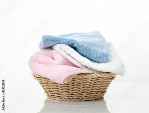 фотографія Folded towels stack in basket on white background,heap of colorful laundry on table
