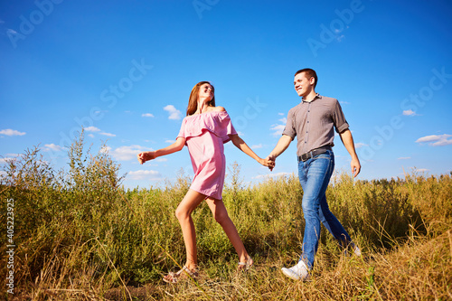 Shot of a young couple holding hands and running through the park.